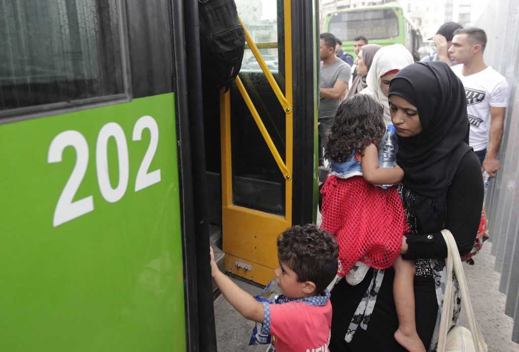 لاجئة سورية وطفلاها يصعدون إلى حافلة في بلدة برج حمود بضواحي العاصمة اللبنانية بيروت عائدين إلى بلدهم، 29/ 8/ 2019 (ا ف ب)