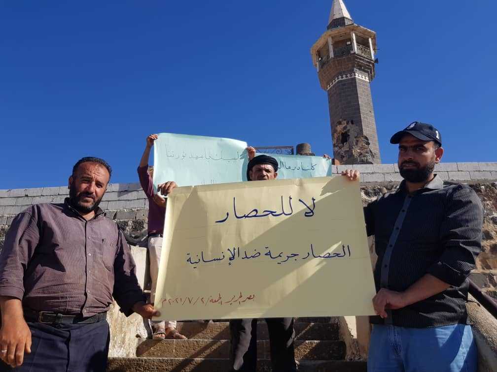 محتجون يرفعون لافتات في بلدة بصر الحرير شرق درعا تعبر عن رفض الحصار الذي تفرضه القوات الحكومية على درعا البلد، 2/ 7/ 2021 (تويتر)