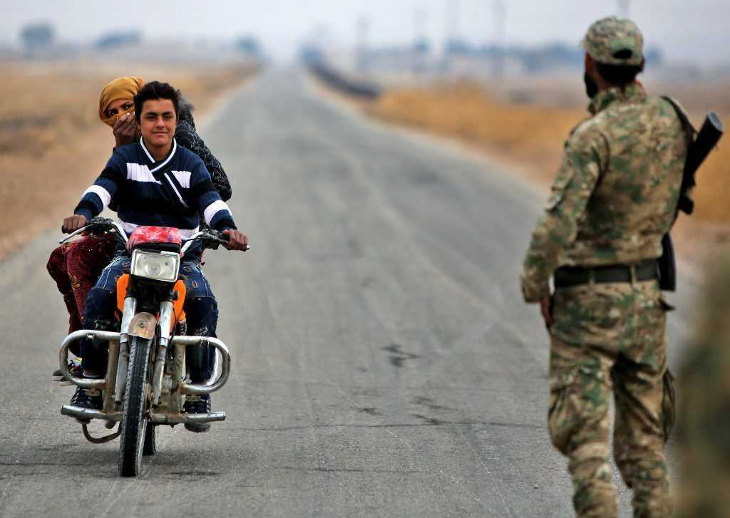 شاب وامرأة يستقلان دراجة نارية بالقرب من حاجز أمني تابع للجيش الوطني المدعوم من تركيا، 25/ 11/ 2021 (أ ف ب)