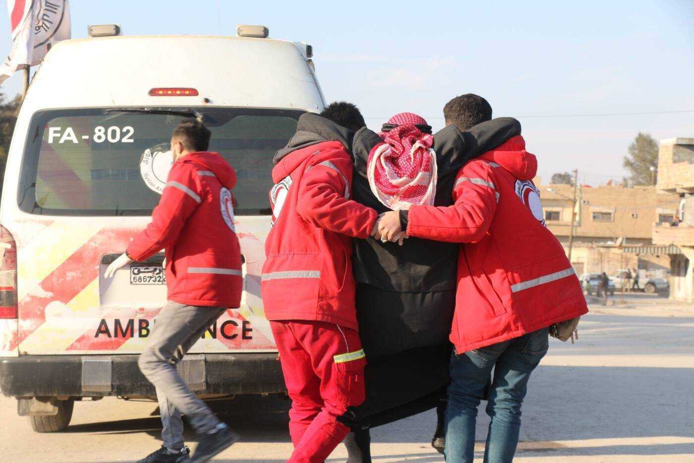 volunteers from the Syrian Ara Red Crescent carry man in front of an ambulance