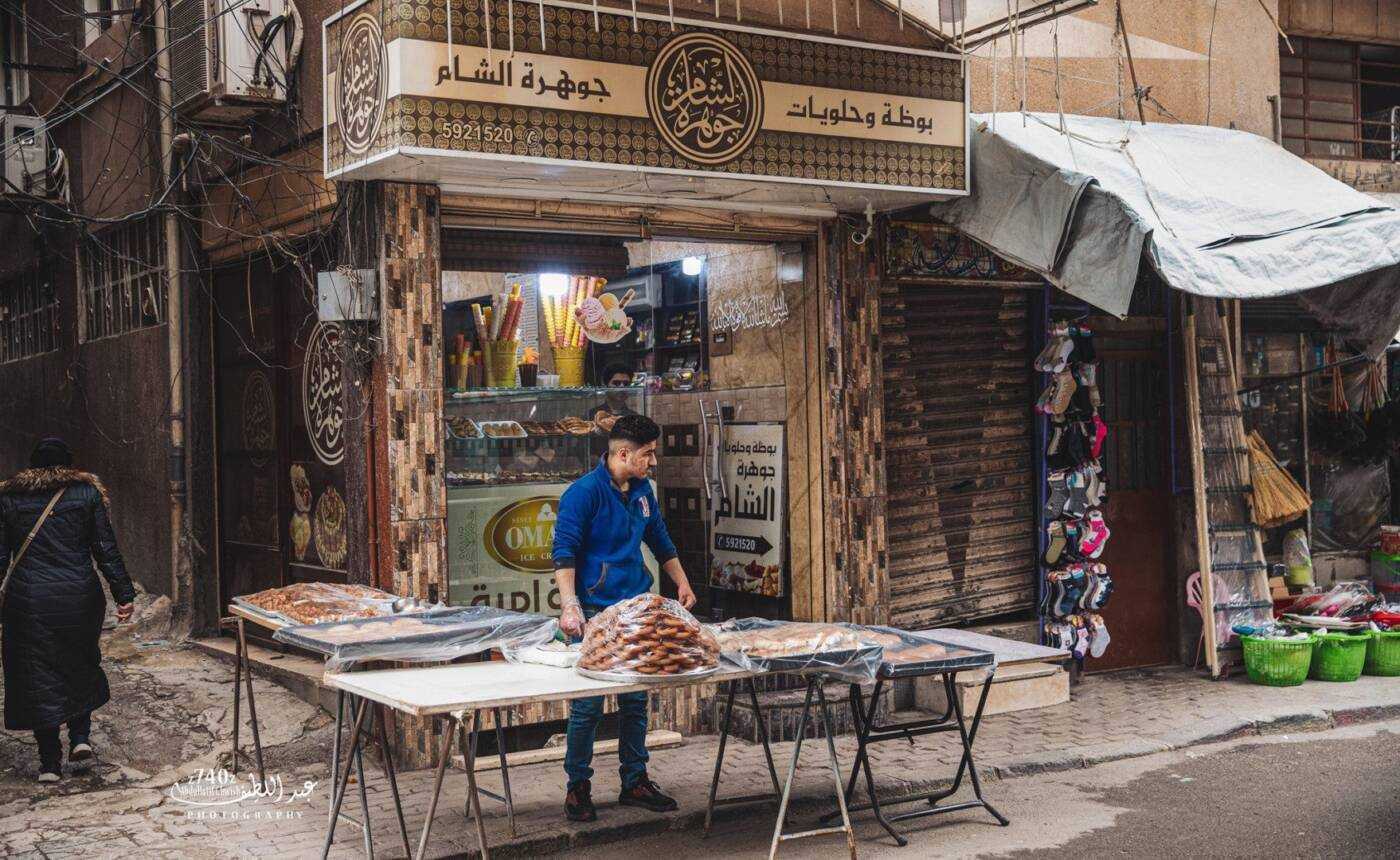 شخص يبيع حلويات رمضانية، أول أيام رمضان، أمام أحد محلات الحلويات في مدينة التل بريف دمشق، 23/ 03/ 2023 (عبد اللطيف غويش)