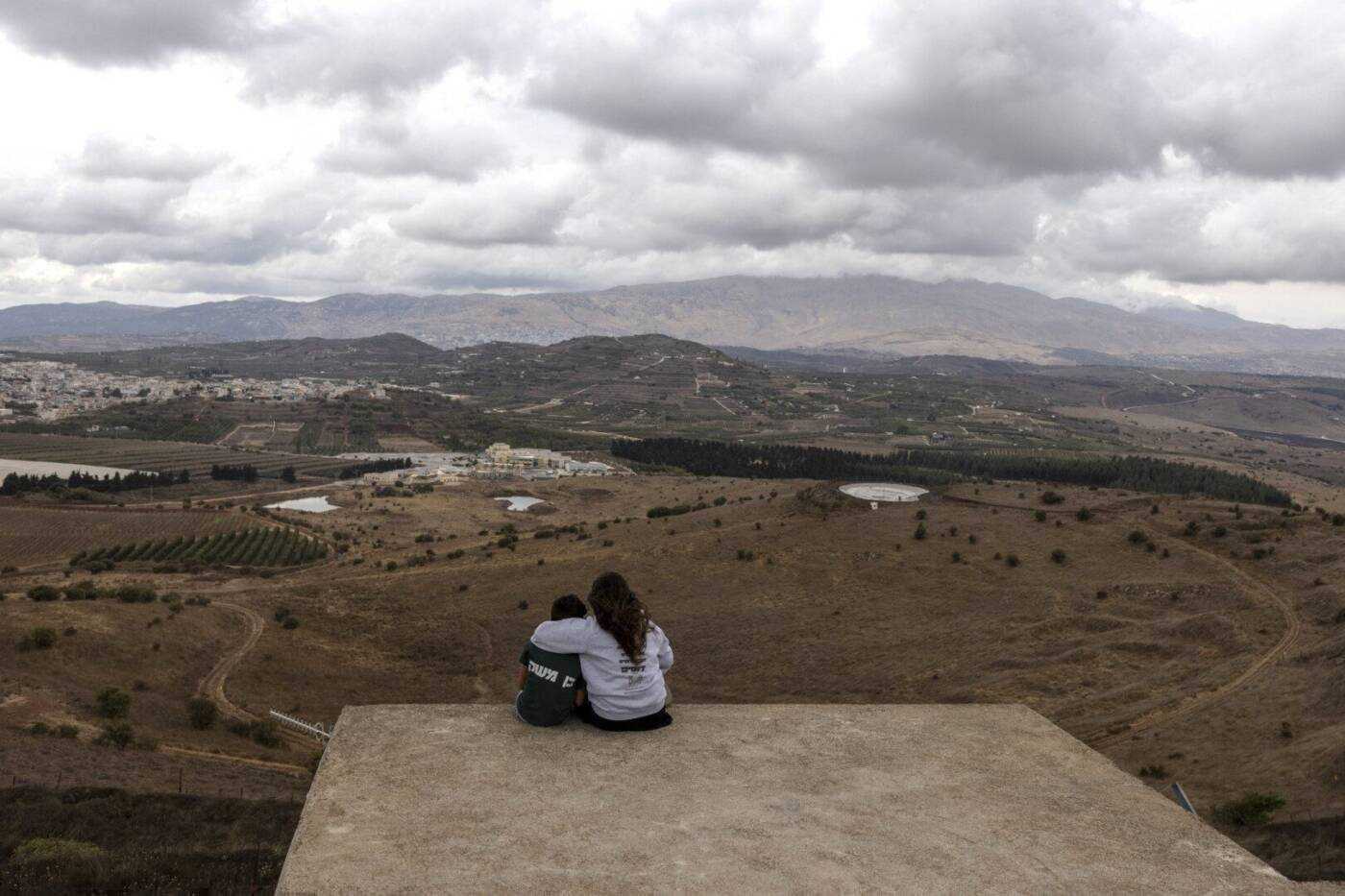 Visitors gaze down at the Israeli-occupied Golan Heights from atop an Israeli army bunker dating from the 1973 Arab-Israeli war, a mere kilometers from the border, where rocket fire from Syria now threatens to bring Syria into the ongoing Israeli-Hamas war, 1/10/2023 (Menahem Kahana/AFP)