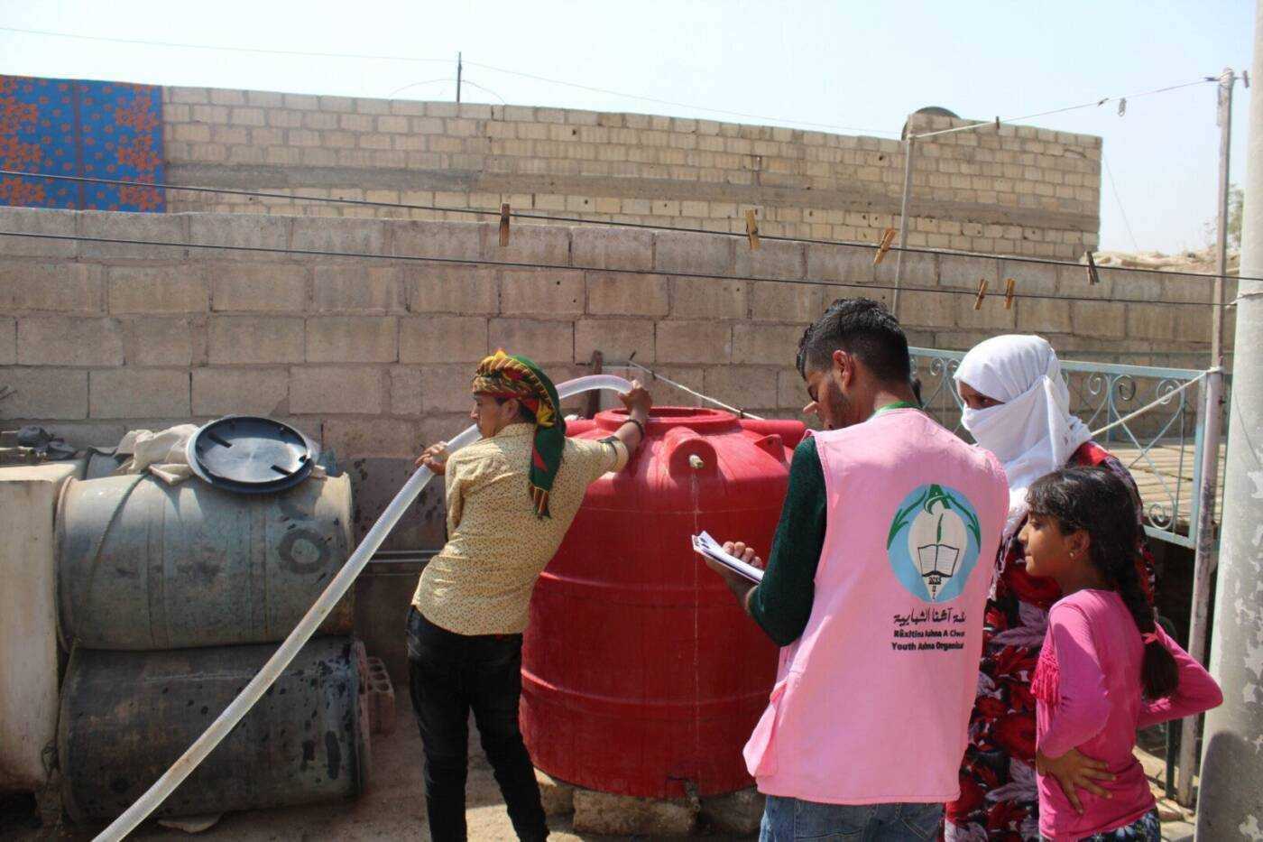 موظف من منظمة آشنا للتنمية يدون معلومات أثناء تعبئة خزان مياه لعائلة في مدينة الحسكة، 06/ 09/ 2020، (آشنا للتنمية/ سوريا على طول)