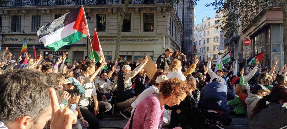 Protesters raise their hands with peace signs in a moment of silence for thousands of lives lost in Palestine during a demonstration in Marseille, 5/11/2023 (Natacha Danon/Syria Direct)