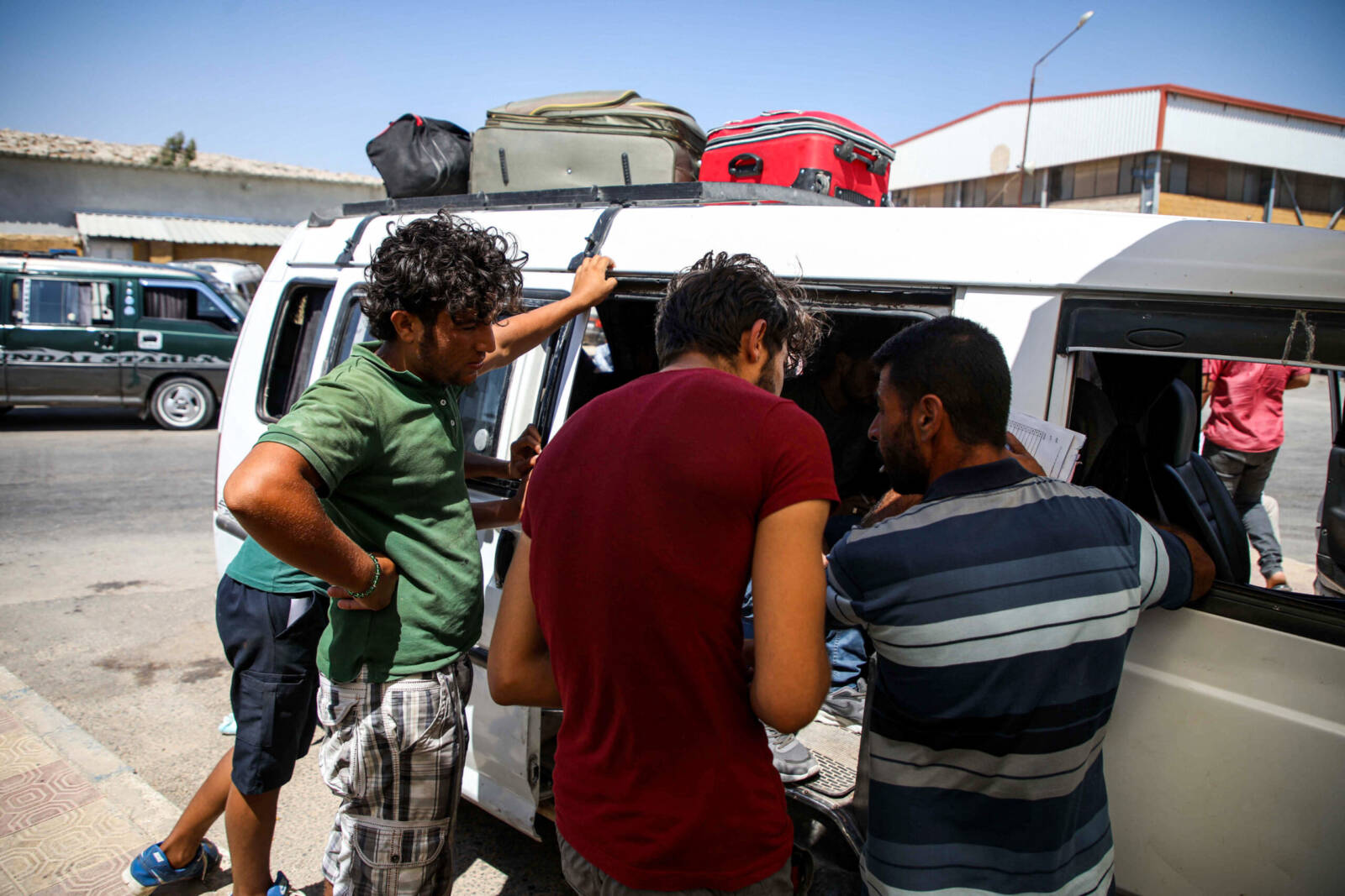 لاجئون سوريون تم ترحيلهم من تركيا، يقفون أمام حافلة في ساحة الانتظار بمعبر باب الهوى الحدودي، 24/ 07/ 2019، (أ ف ب)