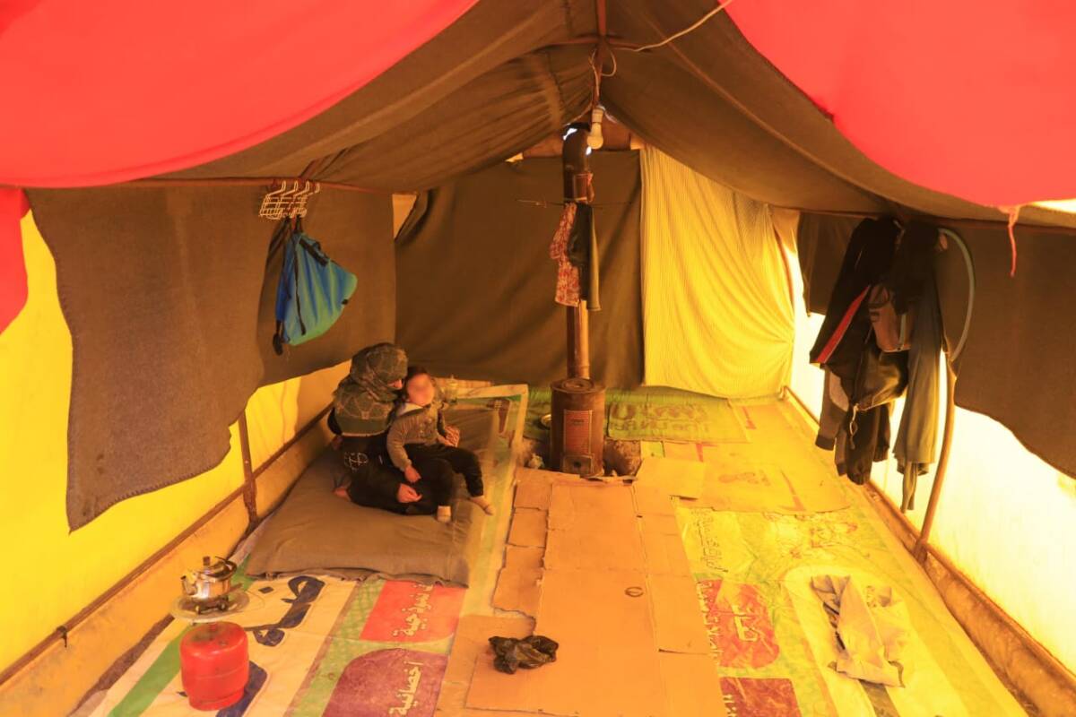 علا العلوش وابنتها تجلسان  قرب المدفأة داخل خيمتهما في جنديرس، 27/ 01/ 2024، (عبد المجيد القرح/ سوريا على طول). 