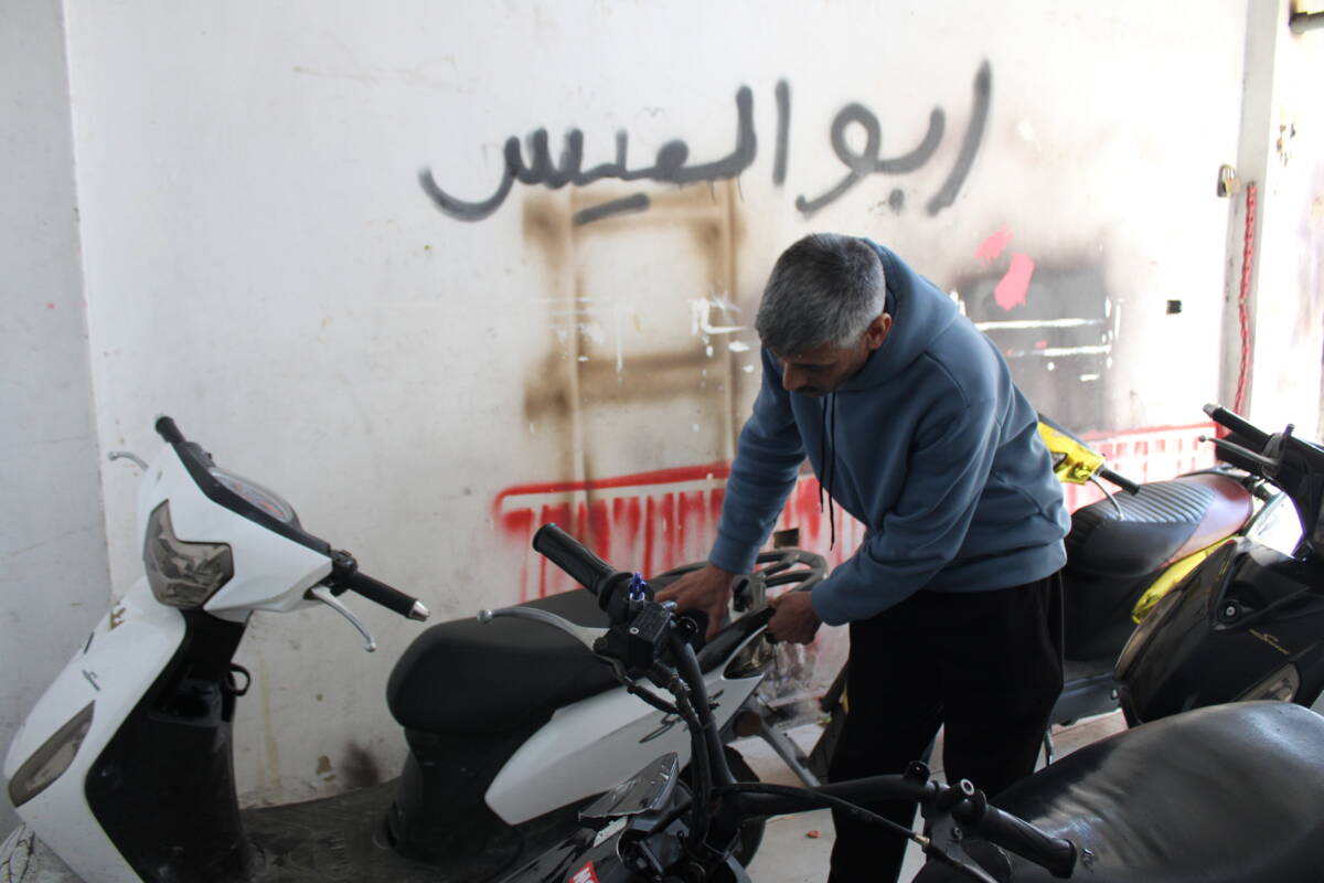 والد ربيع، عيسى محمد العثمان، يتفقد دراجته في كراجه بمخيم برج البراجنة في  بيروت، 27/ 02/ 2024 (هانا ديفيس/سوريا على طول)
