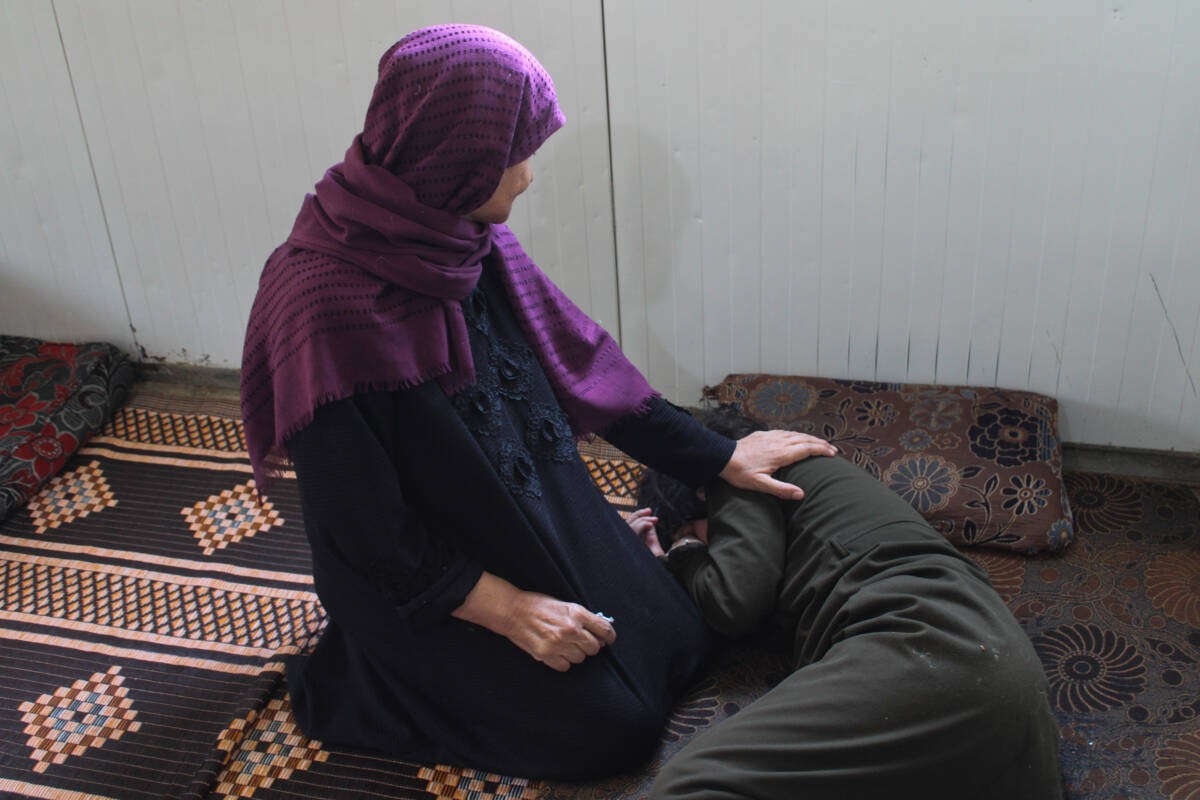 دلال اسماعيل عسكر، 70 عاماً، تجلس في كرفانتهم بمخيم الزعتري إلى جانب ابنتها رغد،  20 عاماً، التي تعاني من شلل نصفي، 03 / 04/ 2024، (هانا ديفيس/ سوريا على طول)