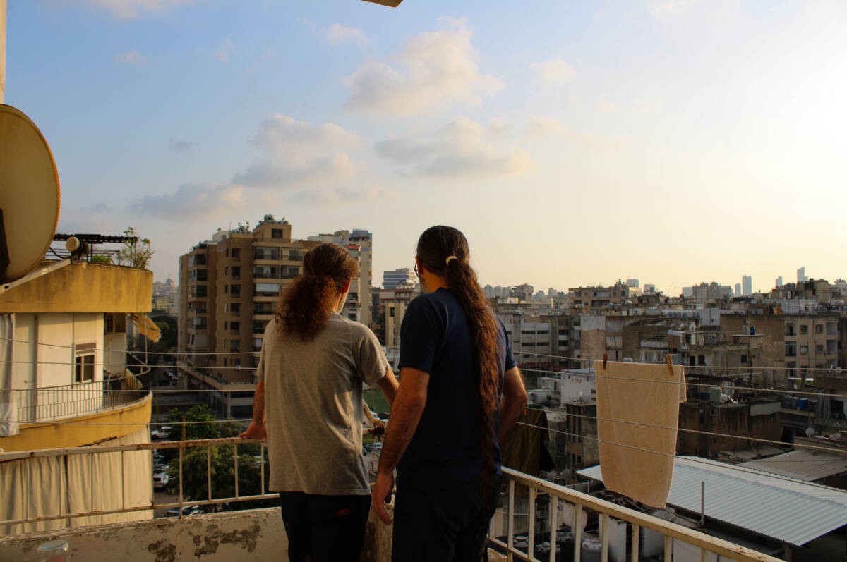 Abed and his brother George, Syrian refugees from Homs, look out from their balcony in Burj Hammoud, a town just east of Beirut, 14/04/2024 (Hanna Davis/Syria Direct)