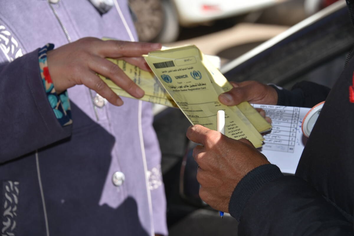 A refugee picks up their yellow card at the UNHCR office in Cairo, 01/02/2021 (UNHCR)