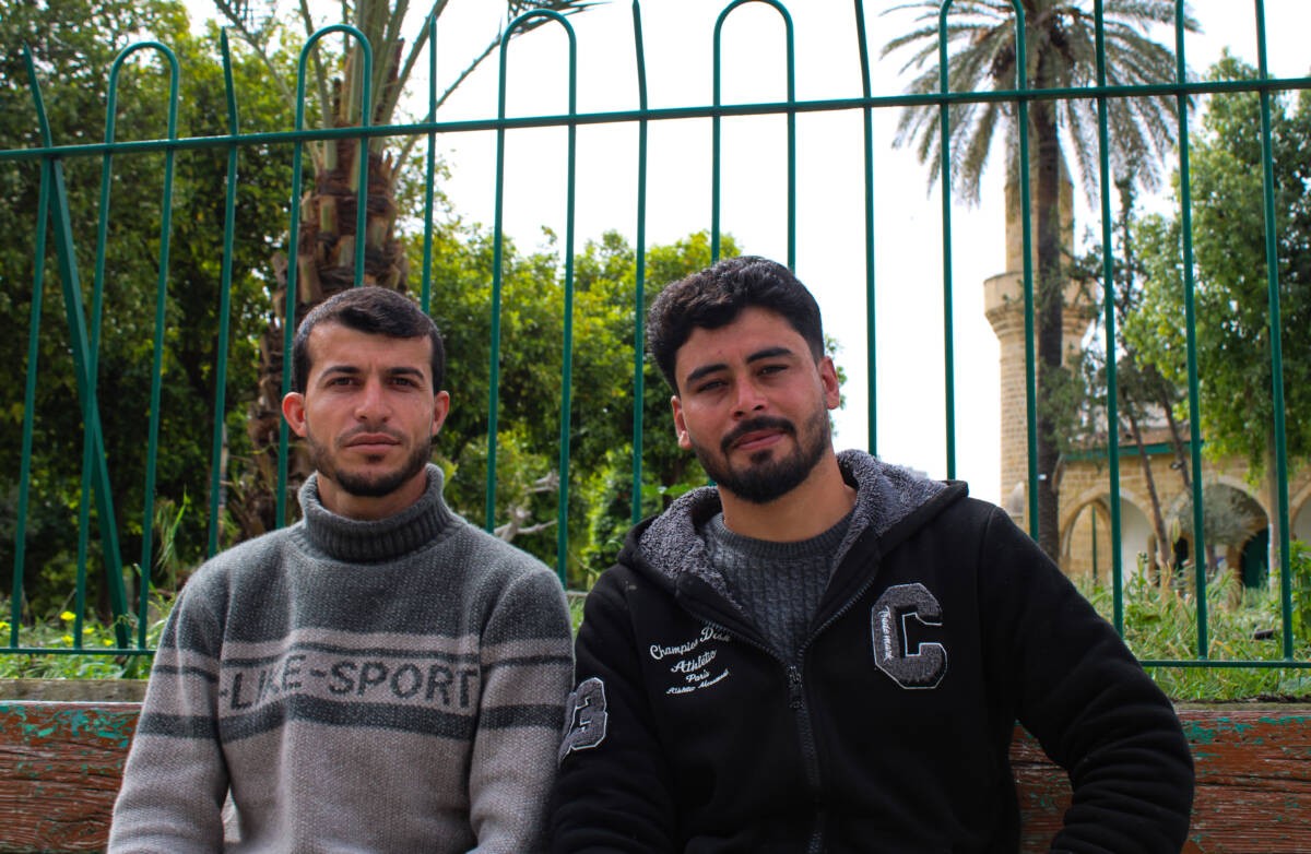 إيهاب الفياض (على اليمين)، 24 عاما، ومحمد أحمد (على اليسار)، 28 عاماً،  يجلسان خارج المسجد حيث ينامان  في نيقوسيا، 29/ 03/ 2024، (هانا ديفيس/ سوريا على طول)