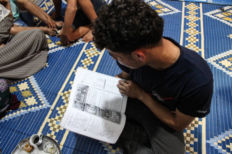 Abed, 17, flips through his English book at his home in Kouba. He recently stopped attending English classes in nearby Tripoli because he fears being arrested and deported while traveling, 3/5/2024 (Hanna Davis, Syria Direct)