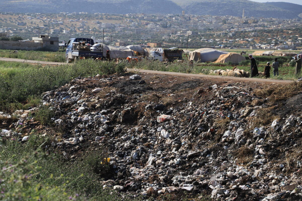 انتشار النفايات على مساحات واسعة بجوار مخيم النسيم في ريف إدلب، الذي يضم 205 عائلات، 03/ 05/ 2024، (عبد المجيد القرح/ سوريا على طول)